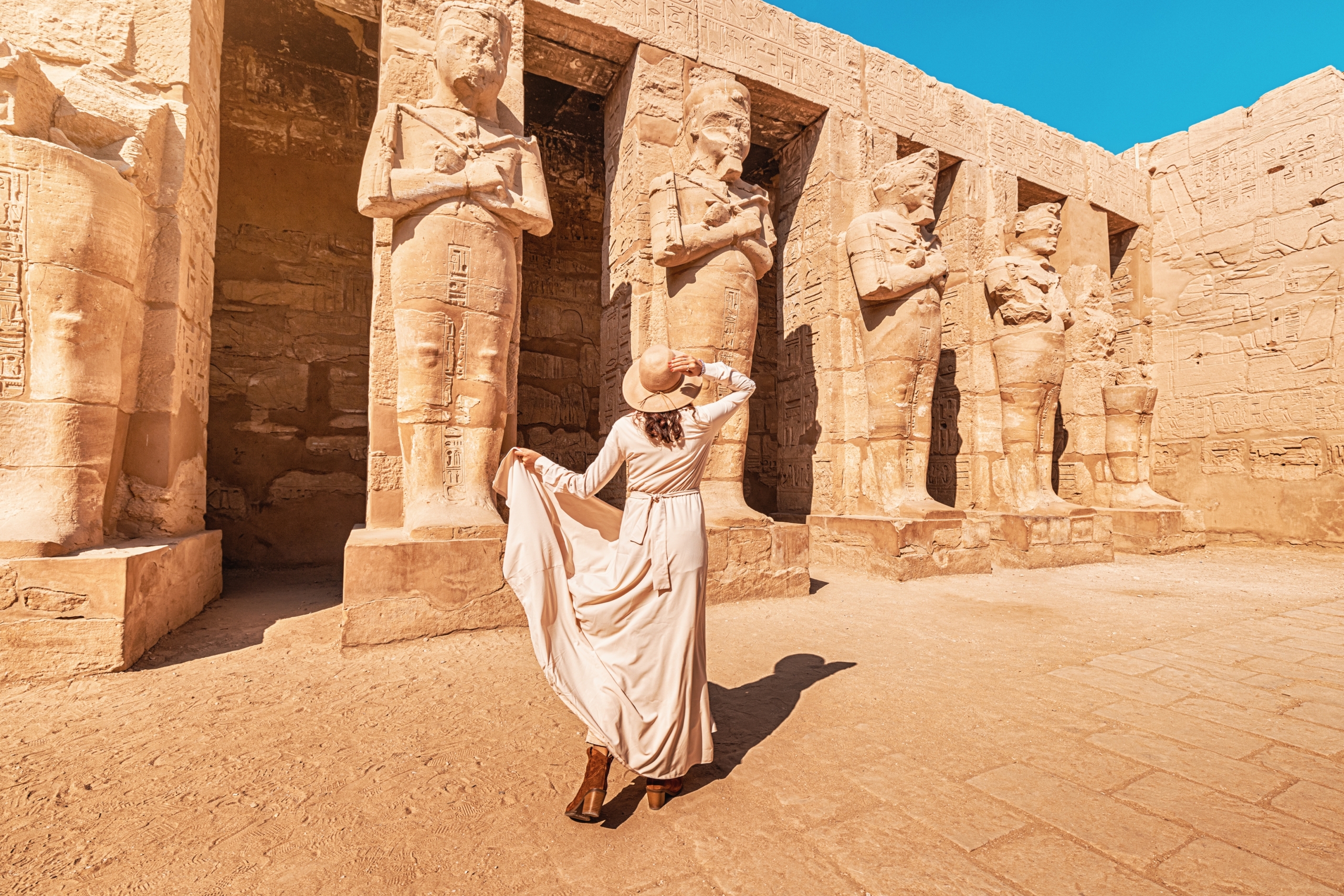 A happy tourist girl in a dress at the Karnak Temple in Luxor